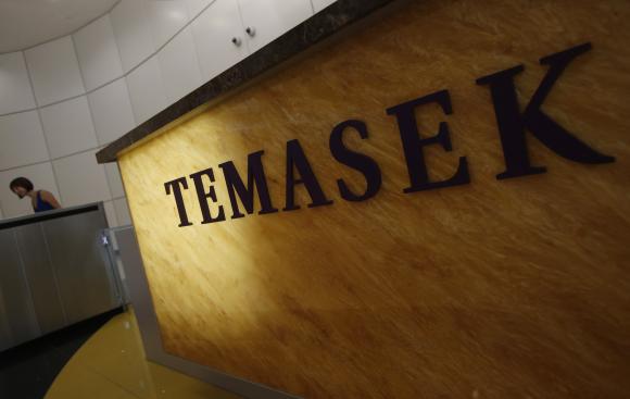 Woman passes a logo of state investor Temasek Holdings at their office in Singapore